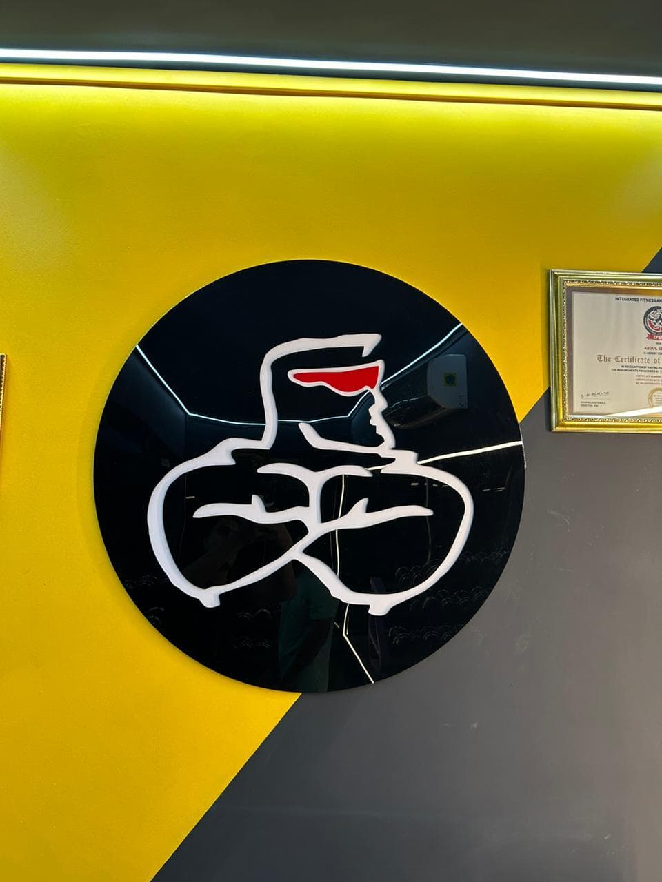 Muscle Mania logo on a yellow and grey feature wall